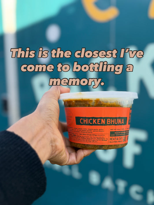 hand holding chicken bhuna plastic container with teal background and letters