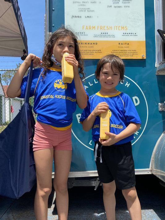 Two children drinking Backyard Buffalo mango lassi at the trailer