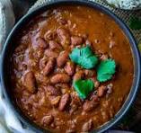 Dish of beans in a rich brown sauce garnished with fresh herbs