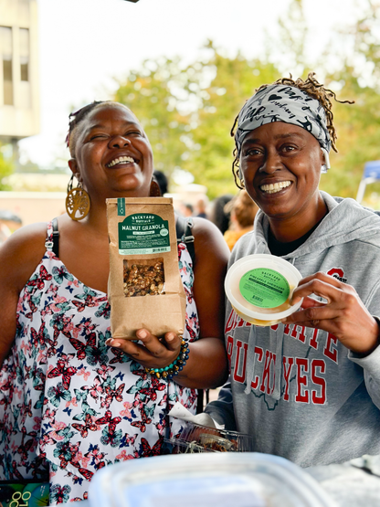 Two friends and customers holding Backyard Buffalo walnut granola and fresh local Indian-style yogurt dessert at Riverside Arts Market